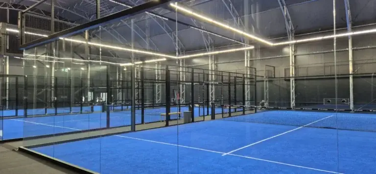 Fedett padelcsarnok tiszta üvegfalakkal és kék műfüves pályákkal a BVSC Cupra Arénában