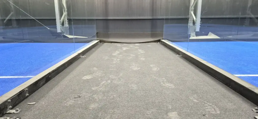 Poros, lábnyomos szőnyeg két padelpálya üvegfala között takarítás előtt, BVSC Cupra Aréna