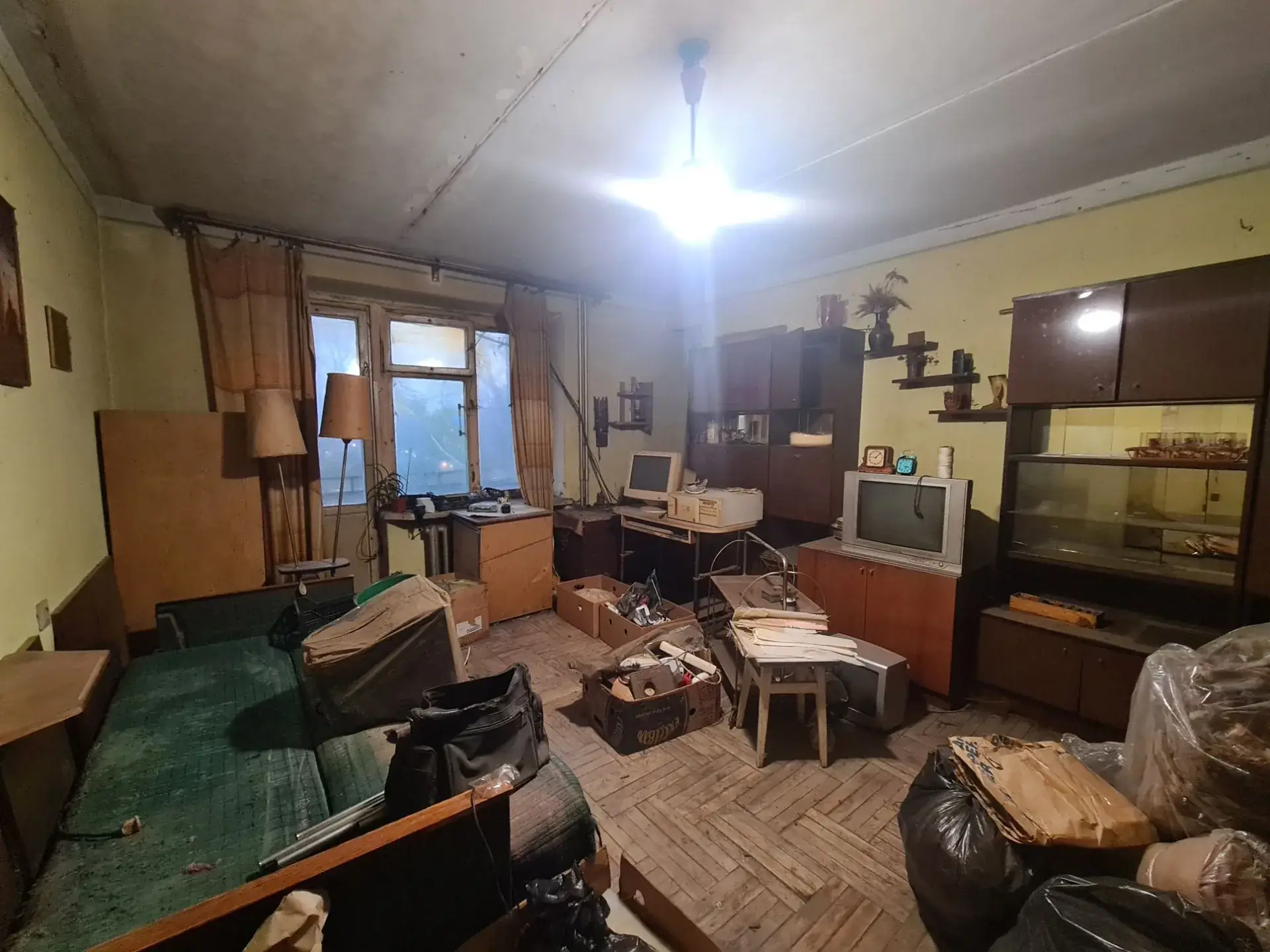Elhanyagolt, zsúfolt szoba dobozokkal és régi bútorokkal extrém takarítás előtt